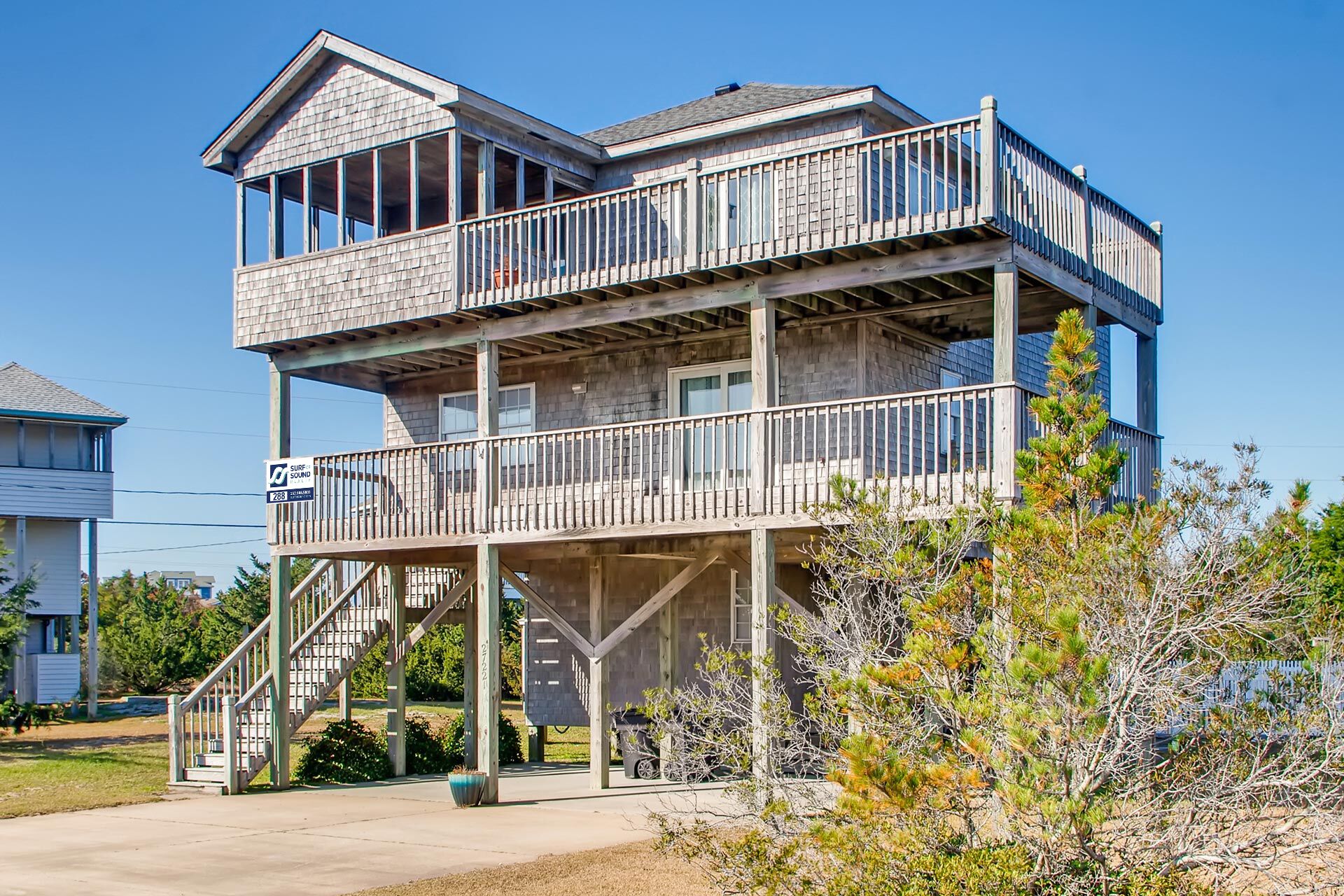 A two-story wooden house with a balcony, a staircase, and a sign indicating a self-sufficient solar fund.