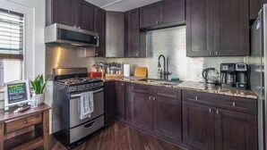 A modern kitchen with dark wood cabinets, stainless steel appliances, and a granite countertop. - Pet friendly studio on 2nd level with a full bathroom and kitchen (Gainesville)