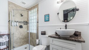 A bathroom with a glass shower enclosure, a toilet, a sink, and a vanity with cabinets. - Pet friendly studio on 2nd level with a full bathroom and kitchen (Gainesville)