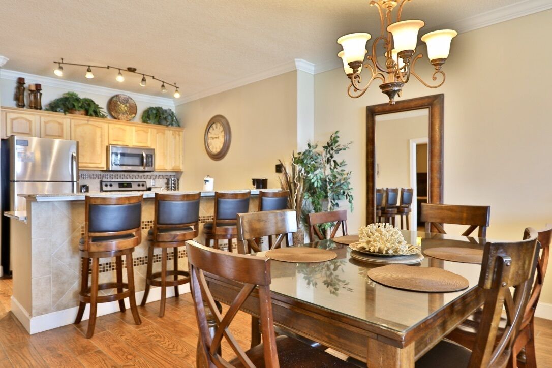 A kitchen with a central island, wooden chairs, a dining table, and a chandelier.