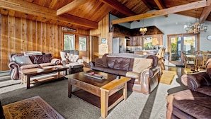 A spacious living room with leather sofas and a wooden coffee table, a kitchen area with wooden cabinets, and a dining area with a wooden table and chairs. - SLOPESIDE CHALET, Near the top of Shay's Revenge / Ski in-Ski out / Great Views  (Snowshoe)