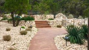 A paved pathway leading to a stone staircase surrounded by rocks and desert plants. - Waterfall Pool, Cabana, Mountain Views, Outdoor Fireplace, 3 Minutes 2 Frio! (Concan)