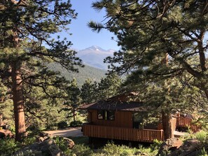 A cabin with a deck, surrounded by pine trees and a mountain view. - Breathtaking Views, Huge Deck, Private, Fireplace, 4 Bedroom 2 Bath, Sleeps 10

 (Estes Park)