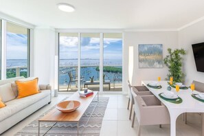 Enjoy a panoramic view of the marina and sea from this living room, featuring a dining area with a table for two and a flat-screen TV.