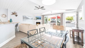 A spacious living area with a glass dining table, a sofa, and a fireplace.