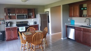 Una cocina con armarios de madera, un refrigerador de acero inoxidable, un microondas y una cafetera.