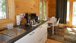 Une cuisine rustique aménagée dans une cabane en bois, avec un évier, une cuisinière et un coin repas.
