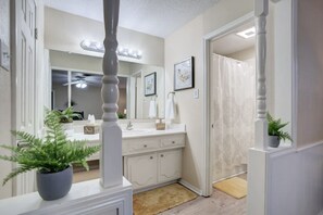 Bathroom features a vanity with sink, towel rack, and potted plant.
