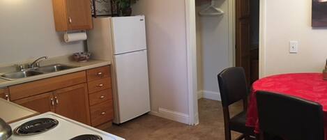 A compact kitchen with a stove, sink, and cabinets, leading to a dining area with a table and chairs.