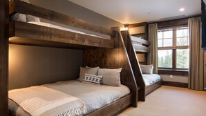 Une chambre avec un lit superposé, une tête de lit en bois, une fenêtre avec des rideaux et un sol recouvert de moquette.