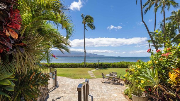 A stone pathway leading to a seating area with a view of the ocean and mountains.