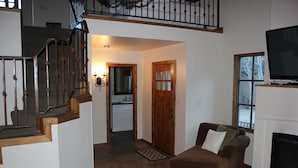 Ein großzügiger Wohnbereich mit Kamin, einem braunen Sofa und einer Treppe zu einer oberen Ebene.