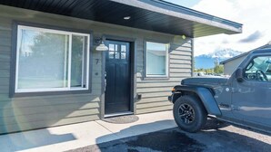 A modern house with a black front door, two windows, and a garage door.