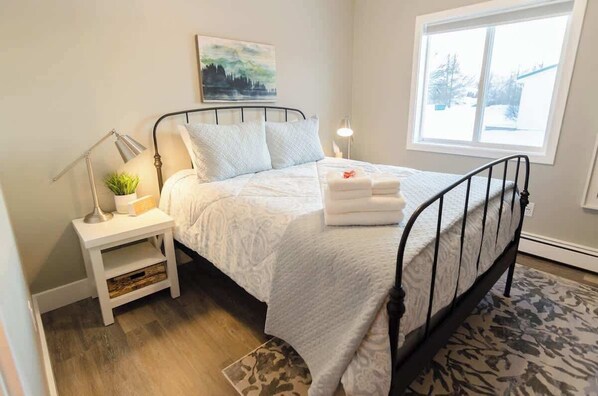 A neatly arranged bedroom with a bed, bedside tables, a lamp, and a window.