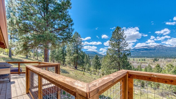 A wooden deck with a metal railing overlooking a mountainous landscape. - Bitterroot Bunkhouse (Hamilton)