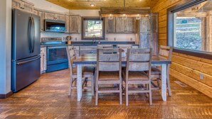 A modern kitchen with wooden cabinets, stainless steel appliances, and a large island with seating. - Bitterroot Bunkhouse (Hamilton)