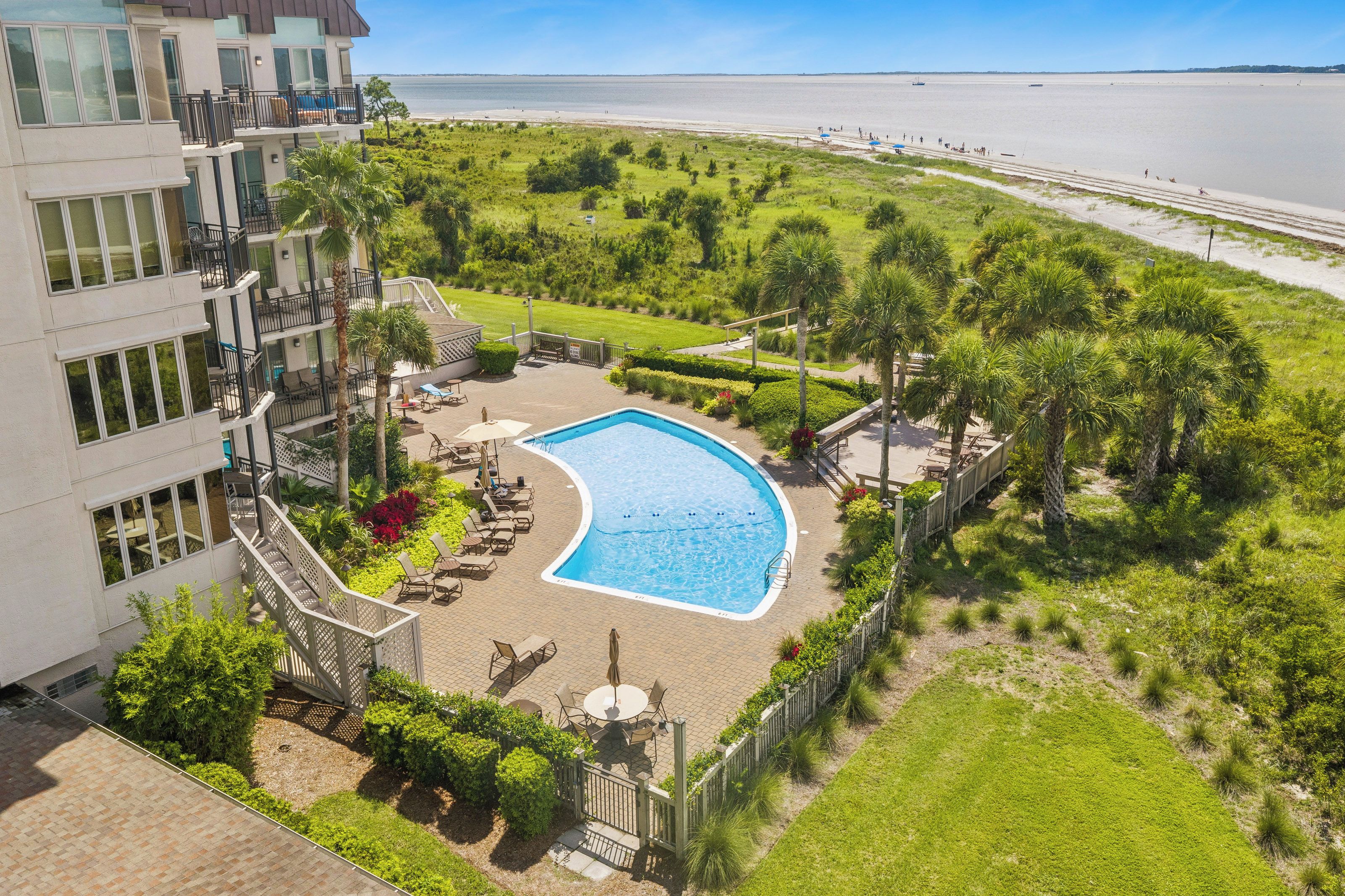 Ein Pool, umgeben von einem angelegten Garten mit Blick auf den Strand.