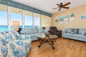 A living room with a view of the ocean, a ceiling fan, and a beach-themed decor. - Beachfront Condo w/ Breathtaking Views & Resort Pool in Destin! 🌊☀🌴 (Destin)
