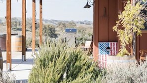 Un'area esterna coperta con travi in legno, vista sul paesaggio e un cartello con la bandiera americana.