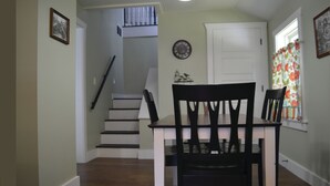 A dining area with a table and chairs, a staircase, and a door. - Gabouri Place ~ Completely Renovated Victorian in Ste. Genevieve's Historic Dist (Ste. Genevieve)
