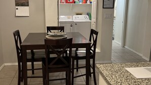 A dining area with a table and chairs, a kitchen with appliances, and a laundry room. - Gated Community, Poolside, Newly Remodeled 2bed Condo (Phoenix)