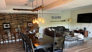 A dining area with a wooden table and chairs, a stone wall, and a mounted television.