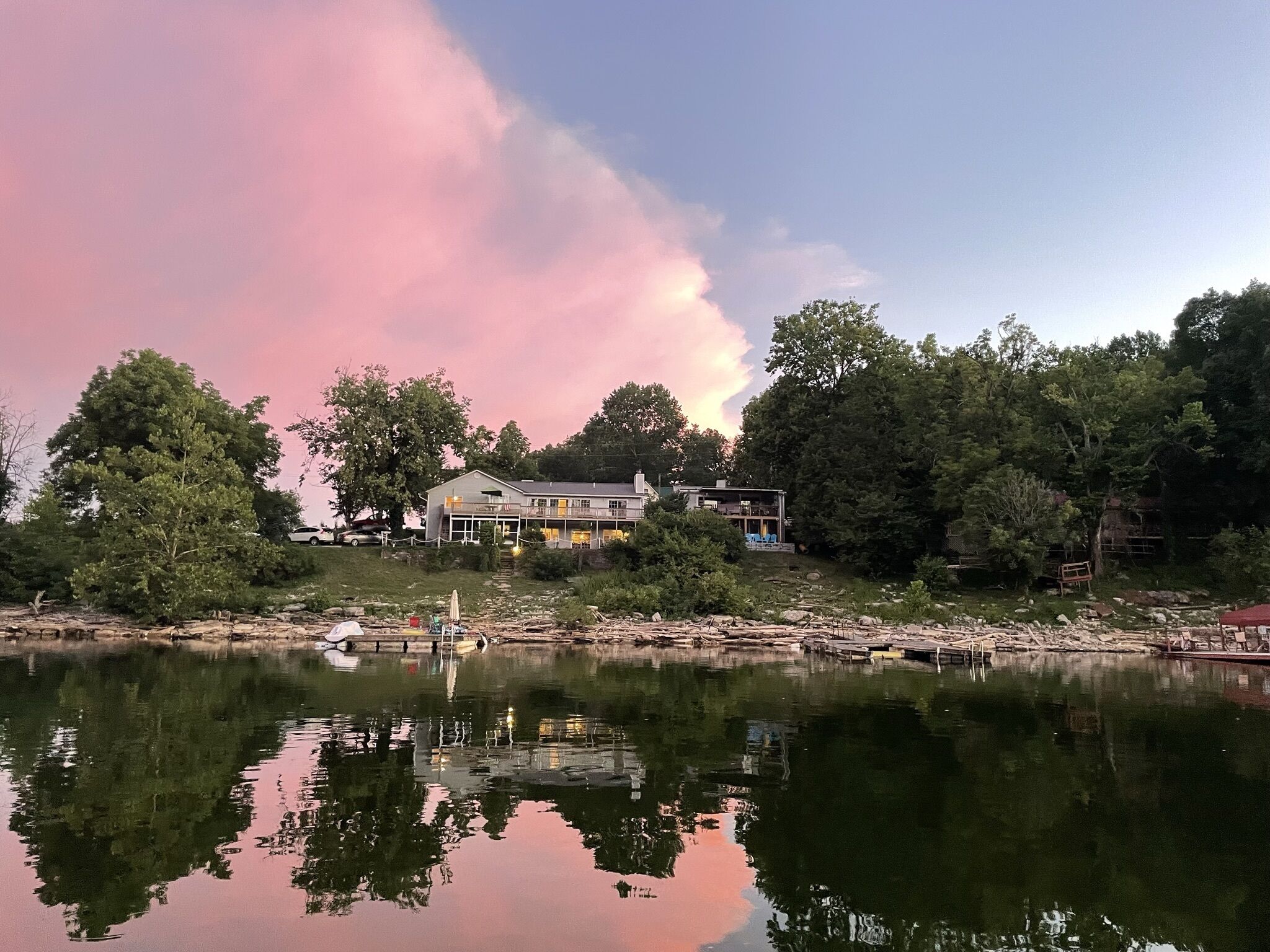 A lakeside property with a large house, dock, and surrounding trees.