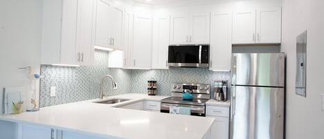 A modern kitchen with white cabinets, stainless steel appliances, and a tiled backsplash.