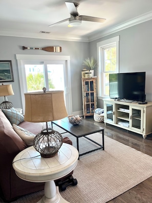 A living room with a ceiling fan, a television on a cabinet, a lamp, a sofa, and a coffee table.