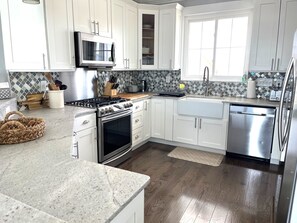 A modern kitchen with white cabinets, stainless steel appliances, and a tiled backsplash.