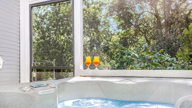 Un bain à remous avec vue sur les arbres, visible à travers une fenêtre.
