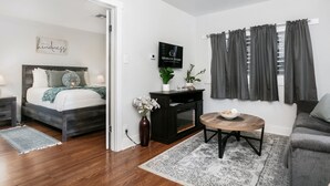 Une chambre à coucher moderne avec un lit, une table de chevet et une petite table d’appoint. On y trouve une petite table sur laquelle sont posés un bol et un vase de fleurs. Une cheminée est visible dans un coin.