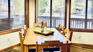 A dining area with a wooden table, chairs, and a hanging light fixture. - Cozy Cabin in the woods  (Munds Park)
