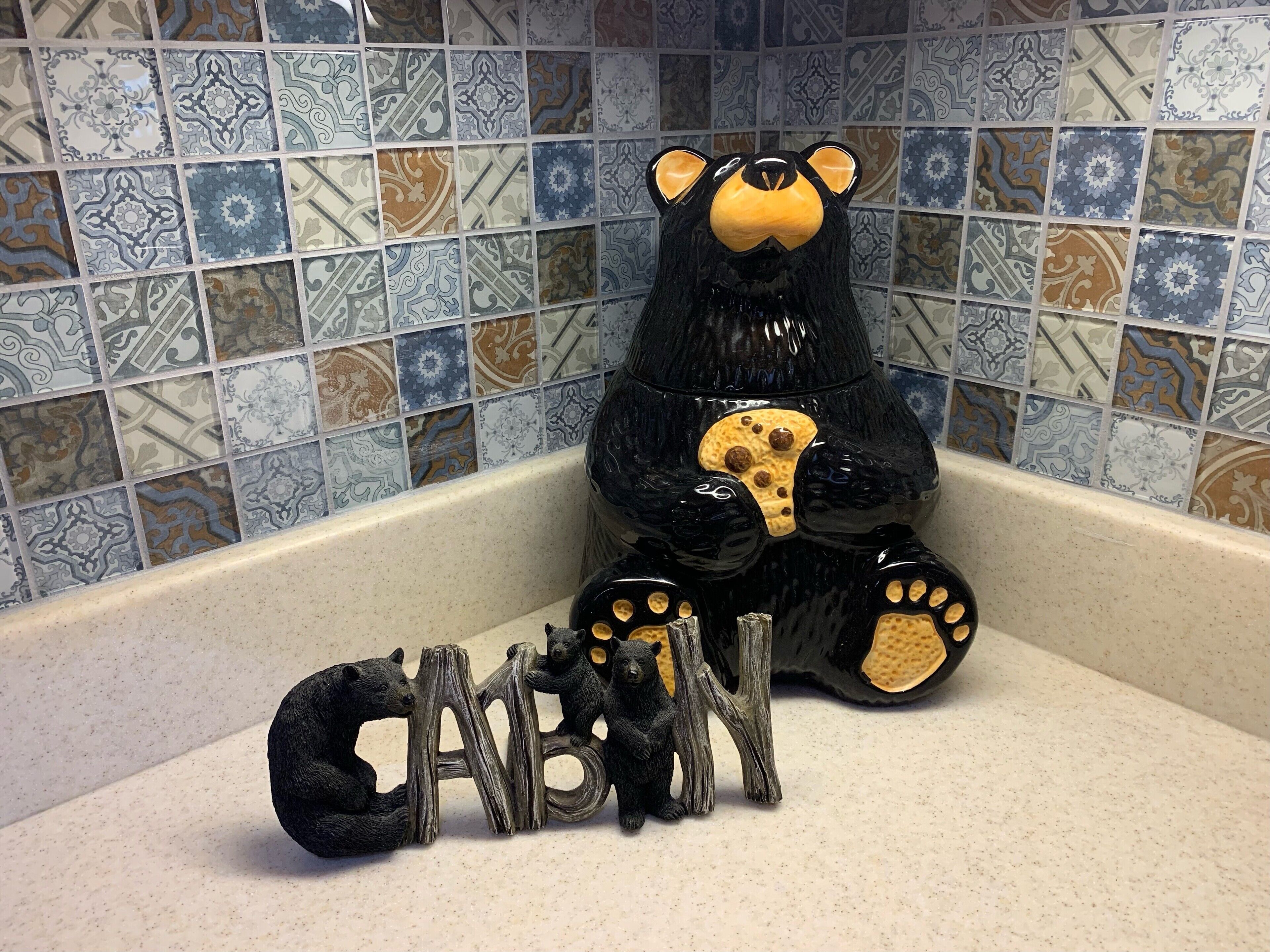 Un porte-savon en forme d’ours, agrémenté d’une figurine d’ours et de lettres en bois épelant le mot « BÉBÉ », posé sur un comptoir.
