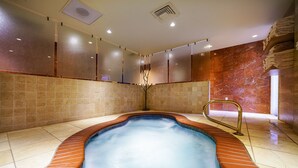Un espace bien-être comprenant un jacuzzi, des murs carrelés et une rambarde en métal.