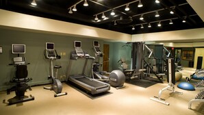 Une salle de sport équipée de tapis de course, de vélos elliptiques et de matériel de musculation.