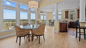 A spacious dining area with a glass table and wicker chairs, overlooking a scenic view. - Premier Oceanfront Dog Friendly w/ Pool, Hot Tub, Elevator, Game & Theater Rooms (Avon)