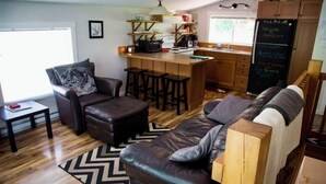 Een gezellige woonkamer met een leren bank, een bijzettafeltje en een bar met krukken.
