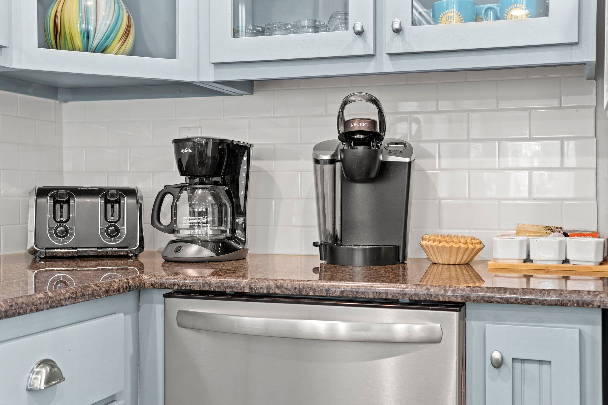 A modern kitchen with a coffee maker, toaster, and a dishwasher.