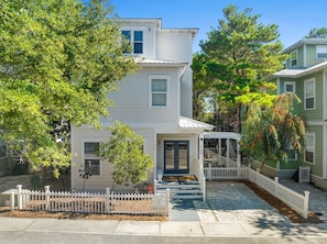 A two-story house with a covered porch, a white picket fence, and a well-maintained yard.