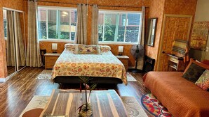 A bedroom with a bed, a bedside table, a fan, a window, and a view of the outdoors. - Sweet Mermaid Studio at Manini Beach, Kealakekua Bay (Captain Cook)