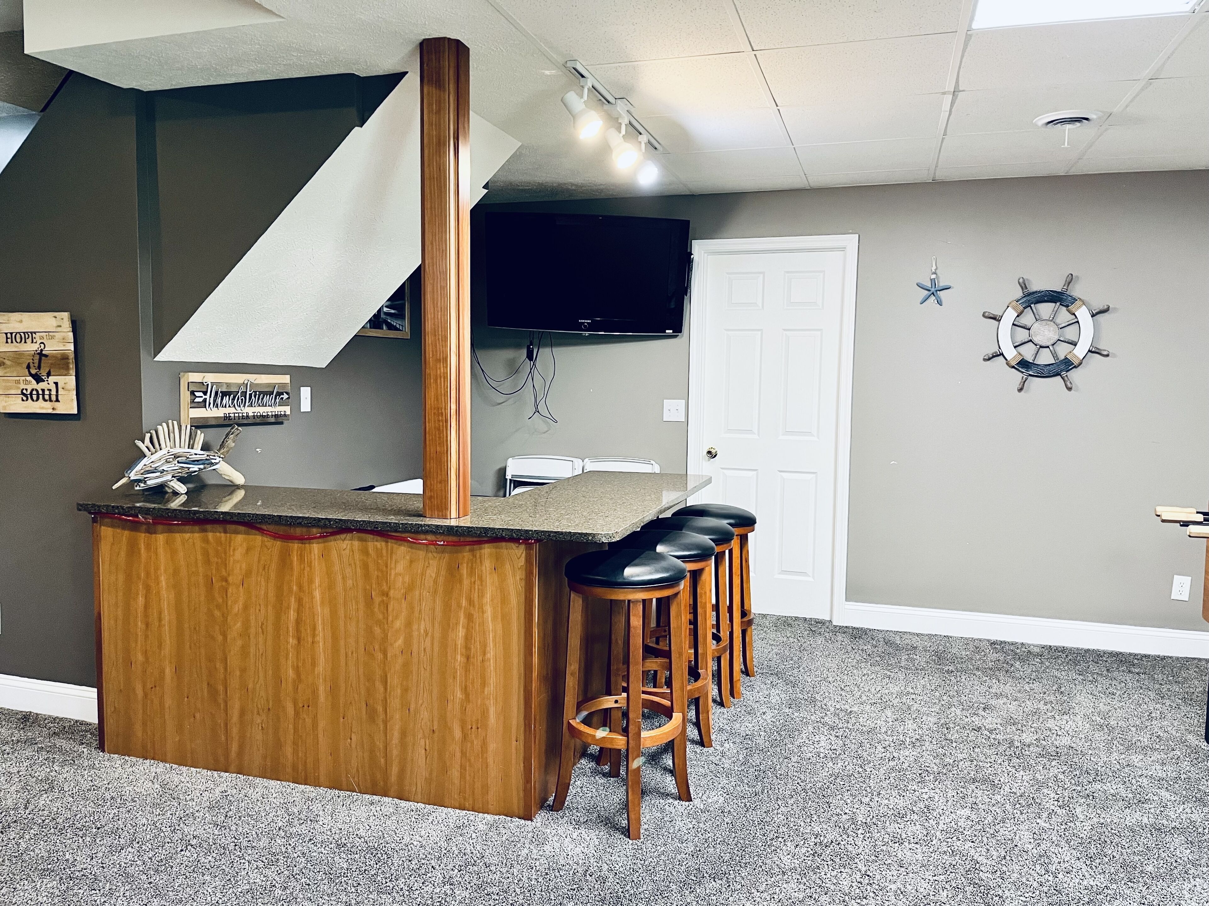 A kitchen with a wooden island, bar stools, a TV, and a door.