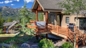 A lodge with a wooden deck, a barbecue area, and a mountain backdrop. - Big Sky Vacation Rentals: MMH 5 Derringer (Big Sky)