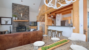 A modern kitchen with wooden accents, a stone wall, and a fireplace. - Big Sky Vacation Rentals: MMH 5 Derringer (Big Sky)