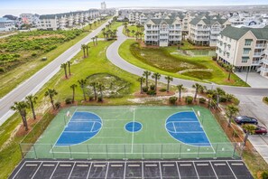 Vista aérea de un área residencial con cancha de baloncesto, calles y edificios de apartamentos.