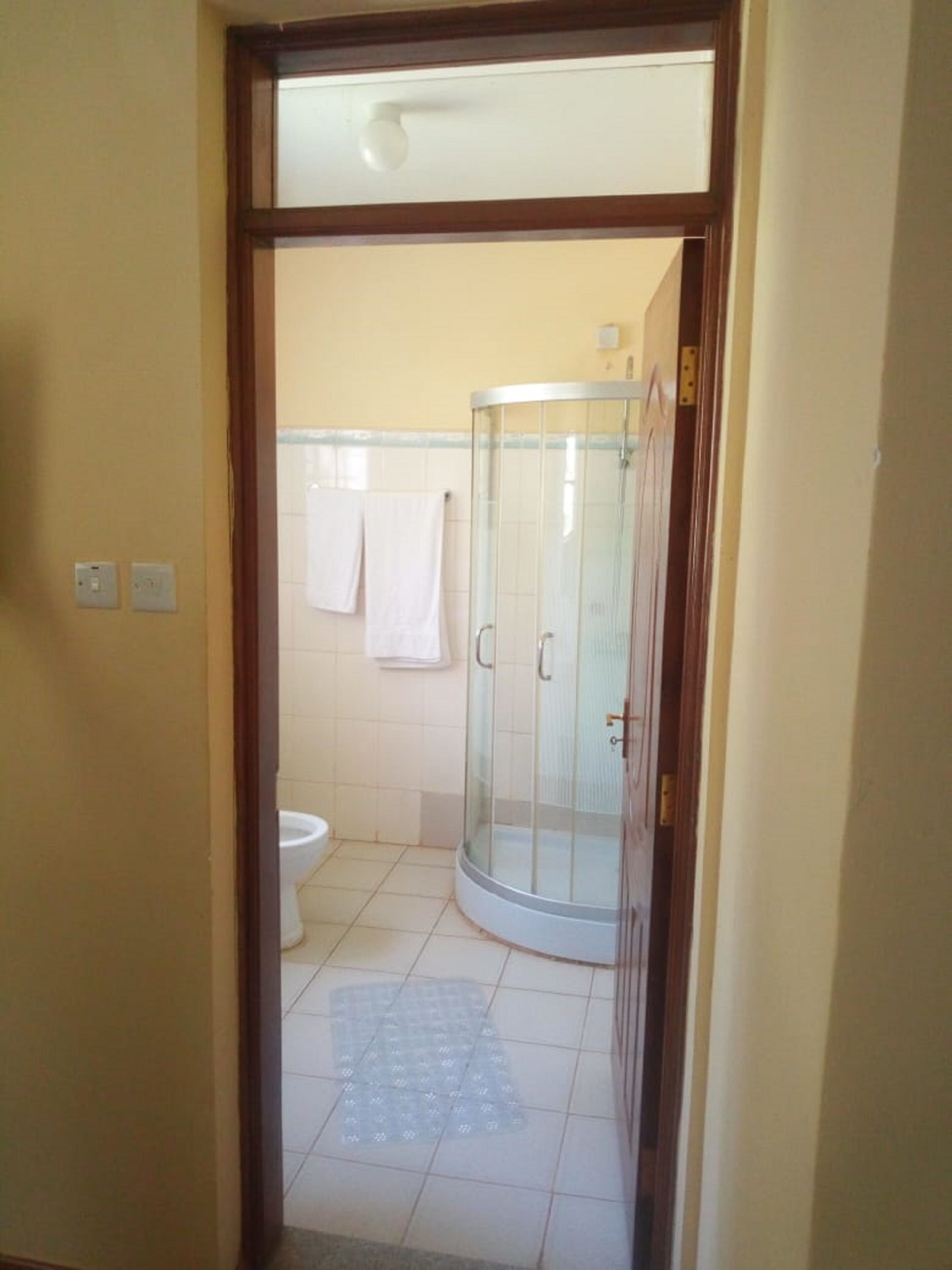 Baño con cabina de ducha de vidrio, inodoro y una toalla colgada en la pared.