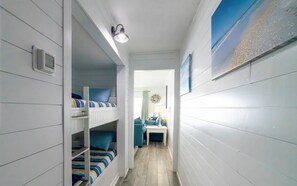 En smal hall med våningssängar på ena sidan och en liten sittgrupp på den andra.