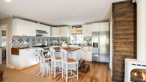 A modern kitchen with white cabinets, a central island, and a built-in stove. - The B’s Hive Cottage (Newbury Park)