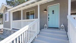 A house with a porch, a light blue door, and white railings. - The B’s Hive Cottage (Newbury Park)