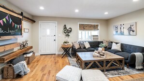A cozy living room with a wooden bench, a sofa, a coffee table, and a door. - The B’s Hive Cottage (Newbury Park)